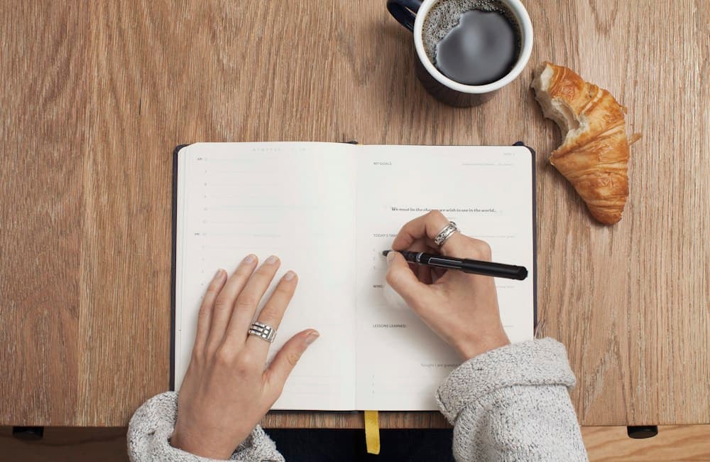 A learner practising writing with notes at a desk